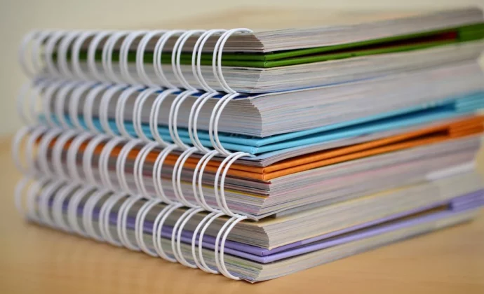A stack of colorful spiral bound books on a table