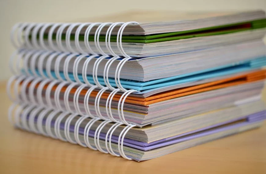 A stack of colorful spiral bound books on a table