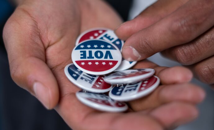 A close up of hands with "Vote" buttons in them