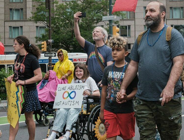 Id…Disabled and non-disabled people walking together in a parade.