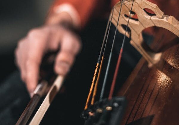 A close up of a person's hand bowing a cello