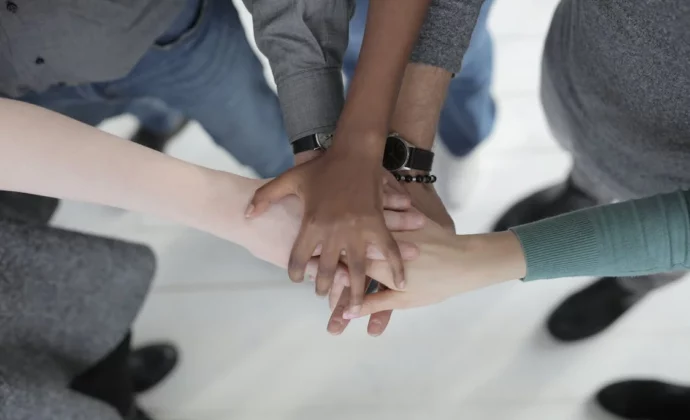 Five people with their hands on top of each other in a huddle
