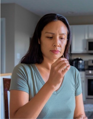 A woman holds a swab to her nose during a Covid test