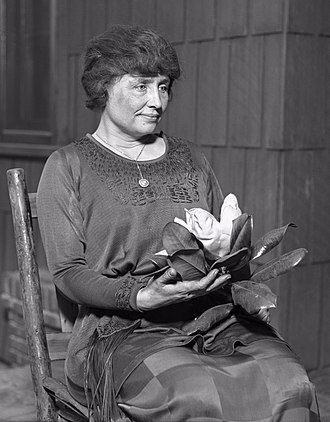 a black and white portrait of Helen Keller sitting in a chair