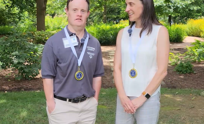 Paul smith and Kristin Ahrens talk in a garden with medals draped around their necks