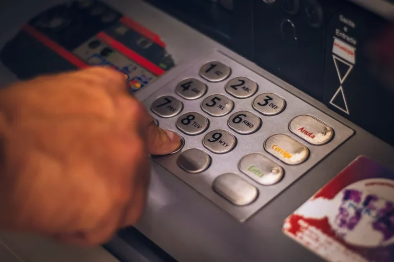 Close up of a mans hand pressing the zero key of an ATM