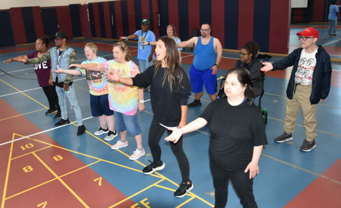 A group of people being led in a zumba glass dancing in a gymnasium