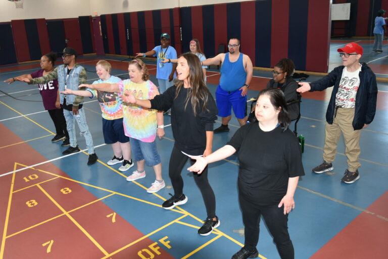 A group of people being led in a zumba glass dancing in a gymnasium