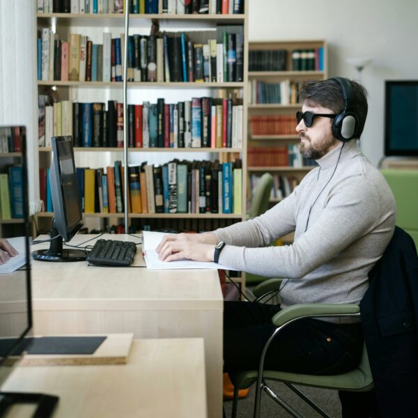 Man using computer with headphones and glasses on