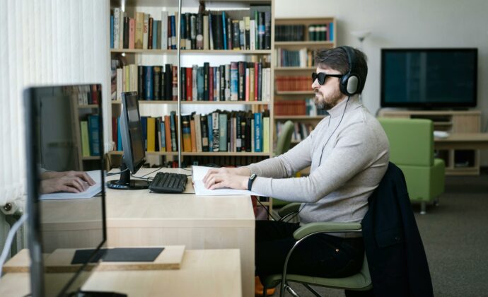 Man using computer with headphones and glasses on