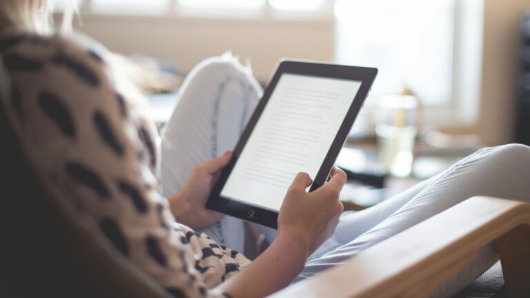 Behind the shoulder of a woman using an ipad