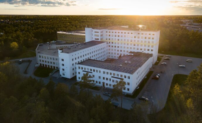 A birds eye view of a hospital surrounded by woods. The sun is peaking over the horizon.